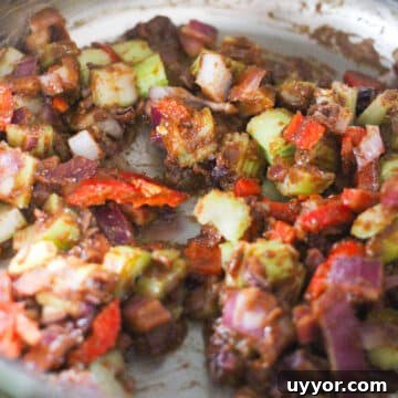 Celery, onions, green pepper being sauteed in a pot.