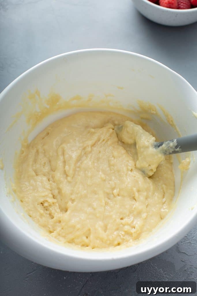 muffin batter in a white bowl with a gray spatula