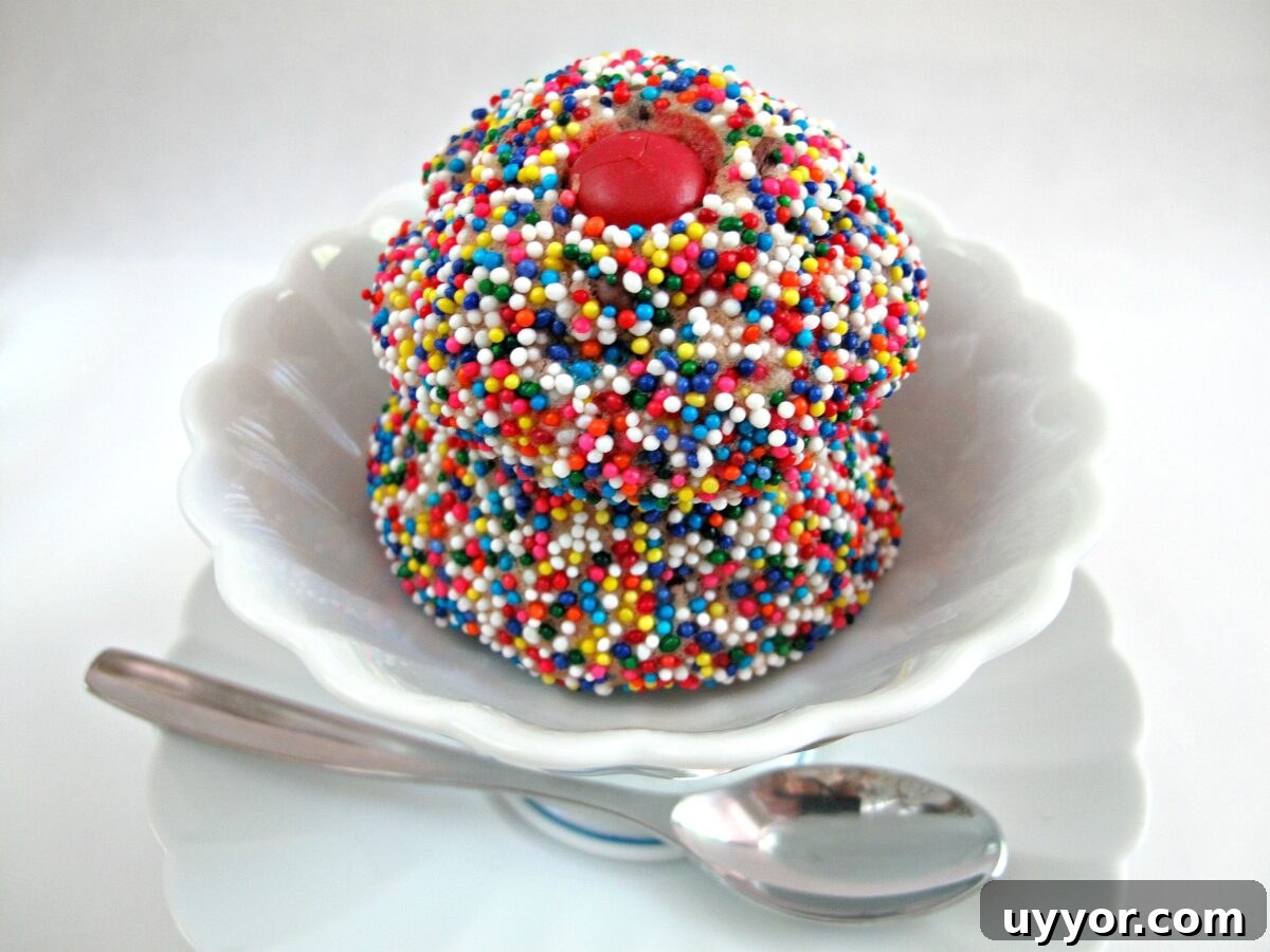 Melted Ice Cream Cookies- dense but tender balls of slightly sweet cookie. Stack of nonpareil covered cookies in an icecream dish.