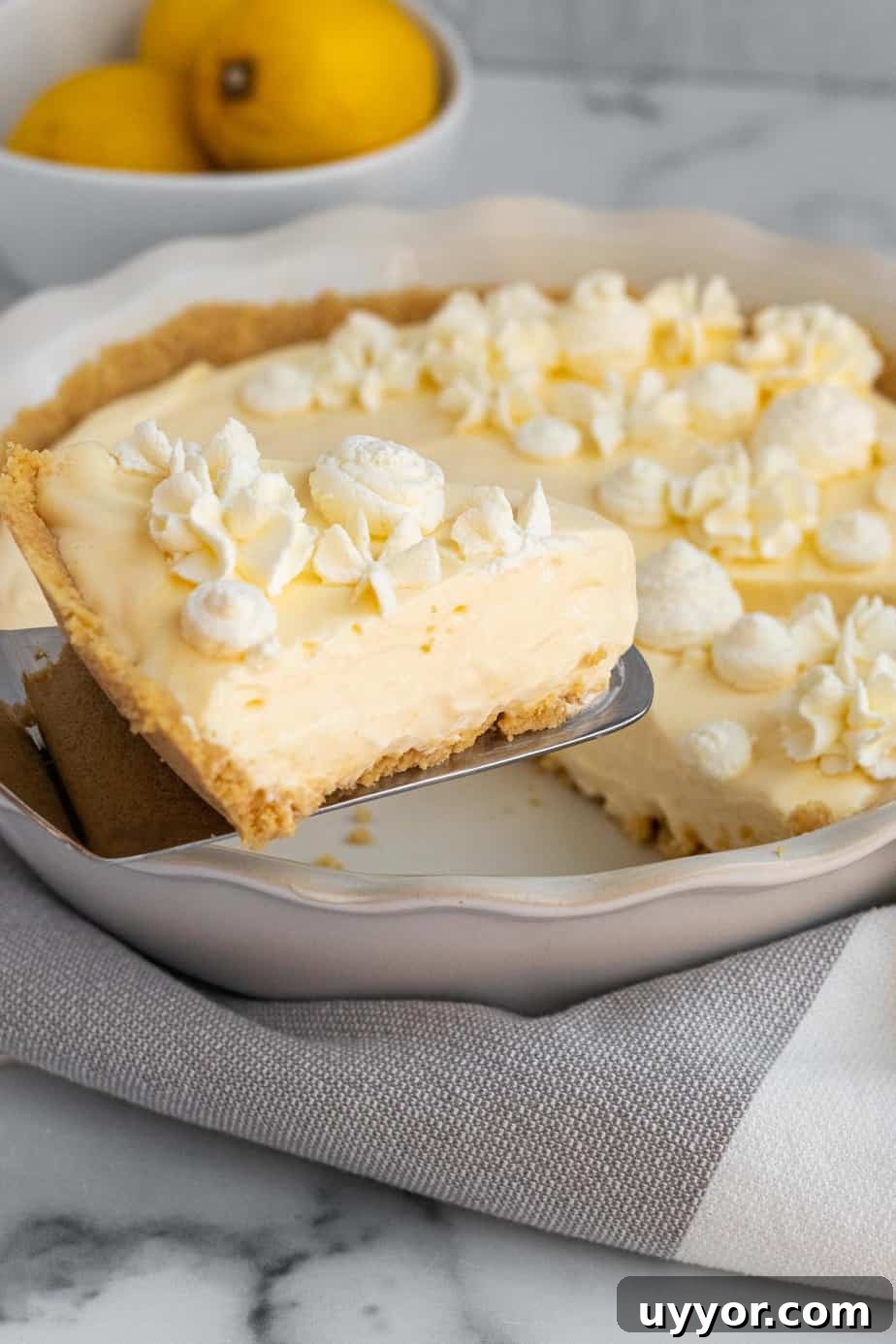 Lemon Cream Pie with Golden Oreo Crust: Zesty No-Bake Dessert 4 slice of lemon pie on spatula being lifted from pie plate
