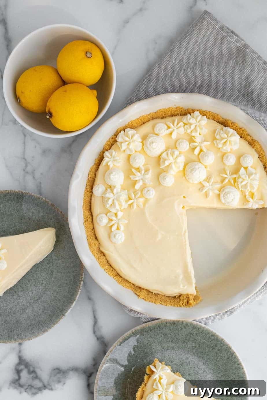 Lemon Cream Pie with Golden Oreo Crust: Zesty No-Bake Dessert 5 2 slices of lemon pie on green plates with bowl of lemons and pie dish