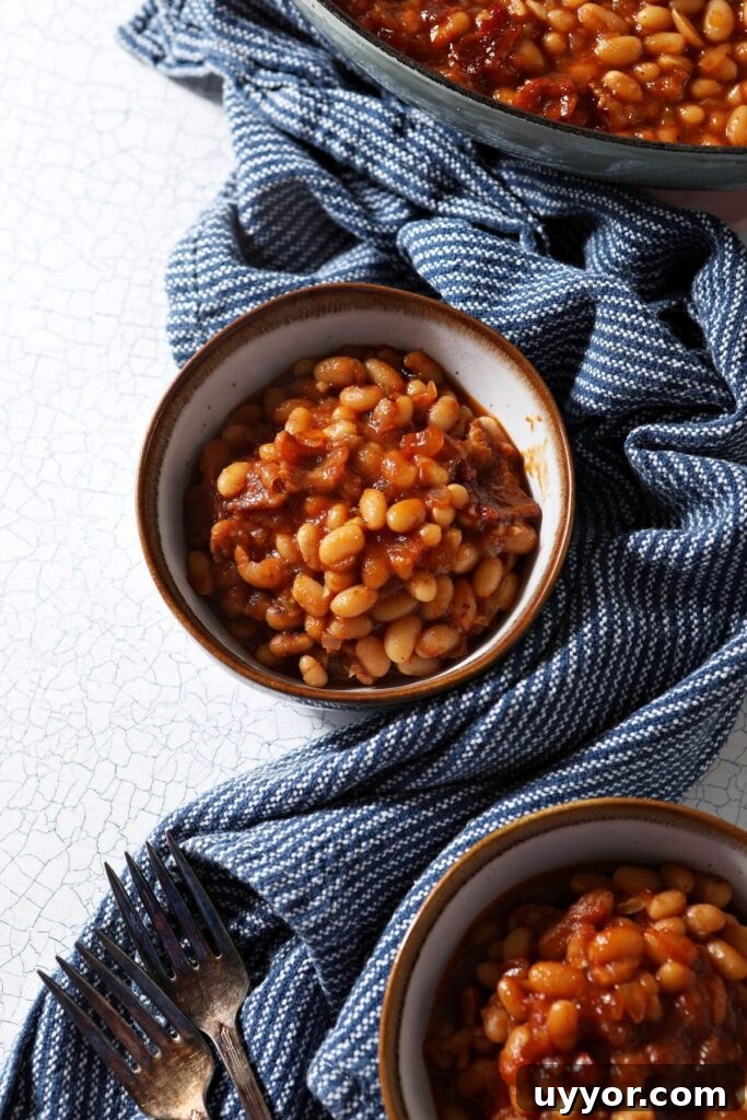 Three bowls of spicy baked beans from above with a blue striped towel