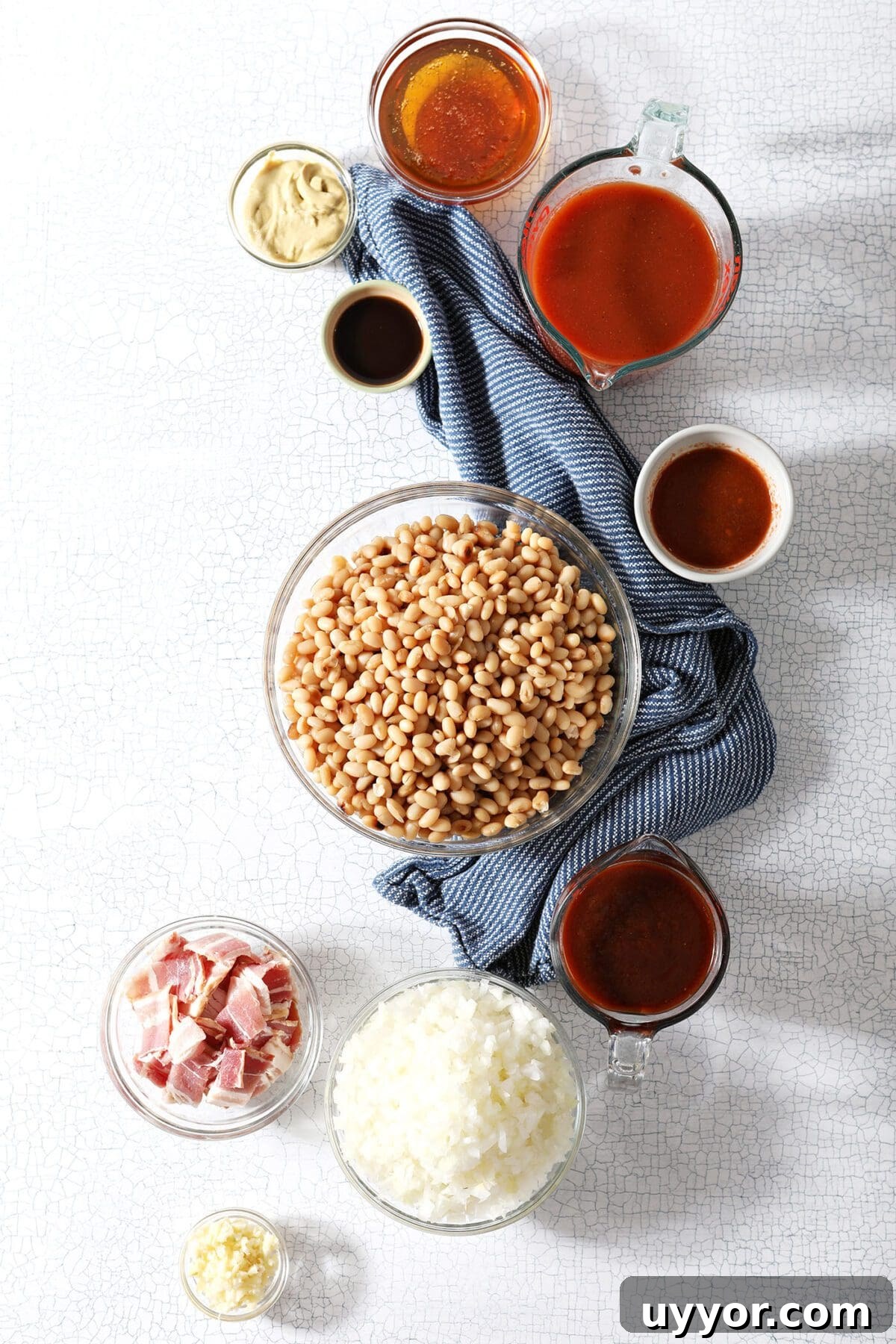 Bowls of beans and other ingredients on marble to make baked beans at home