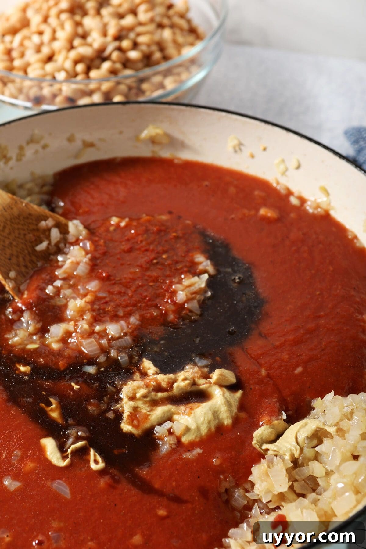 Sauce ingredients on top of the onions and garlic in a braiser pan