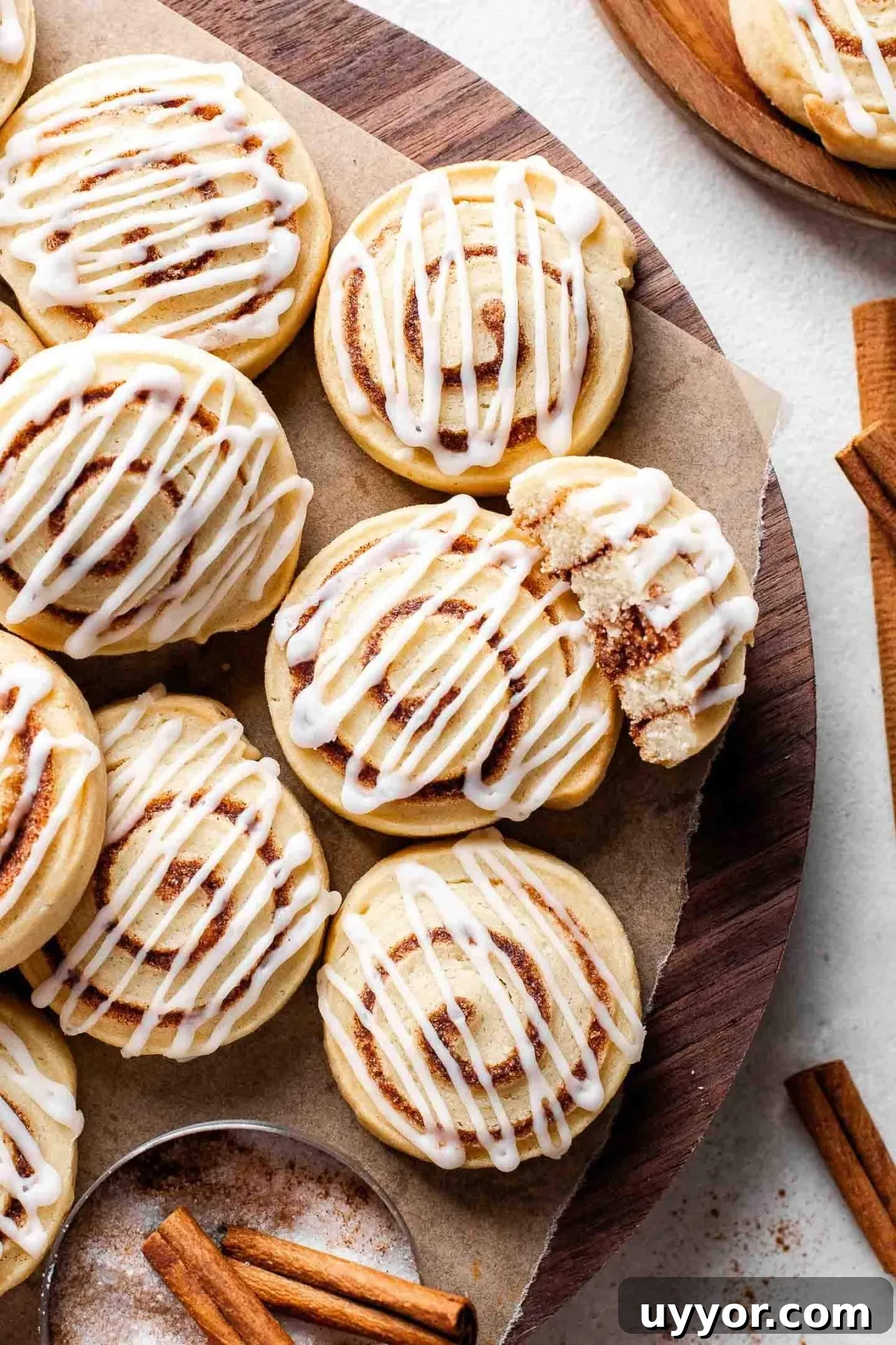Cinnamon Roll Cookie Recipe: Soft Swirls with Cream Cheese Glaze 2 iced cinnamon roll cookies on parchment lined board