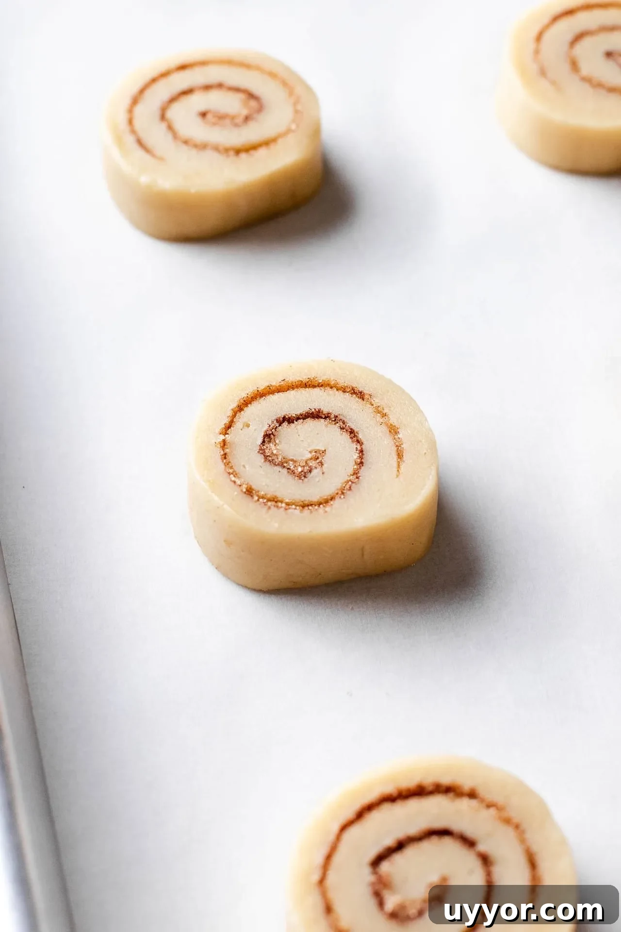 Cinnamon Roll Cookie Recipe: Soft Swirls with Cream Cheese Glaze 9 sliced cinnamon roll cookies arranged on parchment lined baking sheet before baking