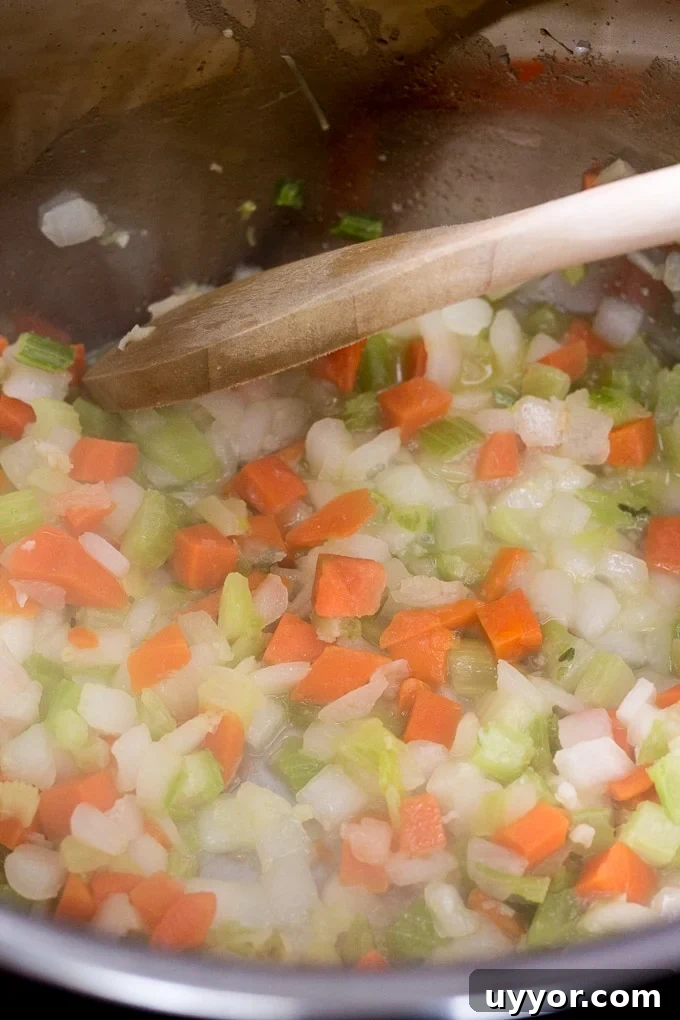 Instant Pot Ground Lamb Soup — Gluten-Free Recipe 3 Mirepoix mix being cooked in an Instant Pot with a wooden spoon.