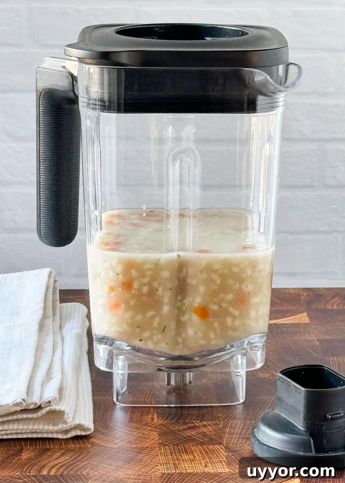 How to Safely Blend Hot Soups and Liquids Without Splashes 3 blender jar filled halfway with chicken rice soup on a butcher block counter
