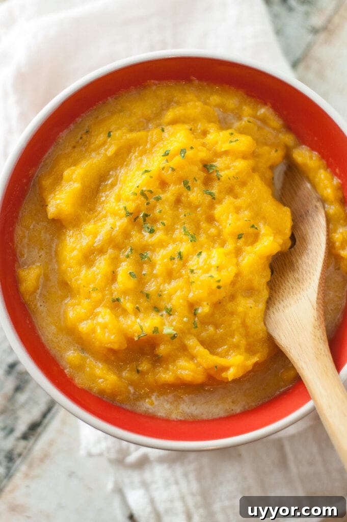 butternut squash in red bowl with wooden spoon