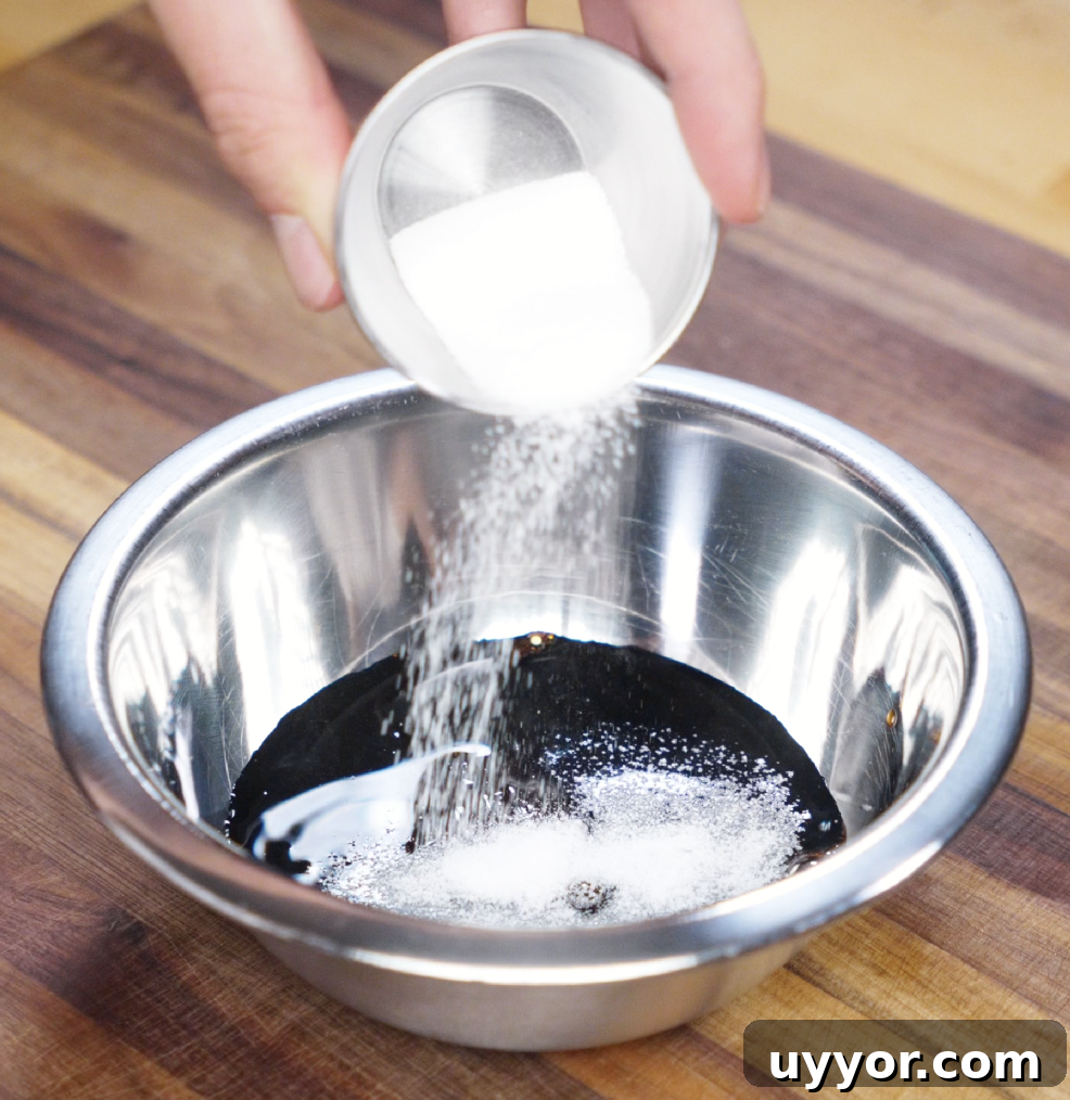 Crispy Pan-Fried Chicken Noodles with Soy-Garlic Sauce 4 Granulated sugar is being poured into a metal bowl filled with soy sauces and oyster sauce. This simple sauce blend brings deep umami and subtle sweetness to the noodles.