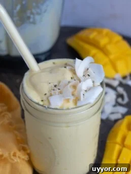 mason jar with a mango protein smoothie topped with coconut flakes and hemp hearts