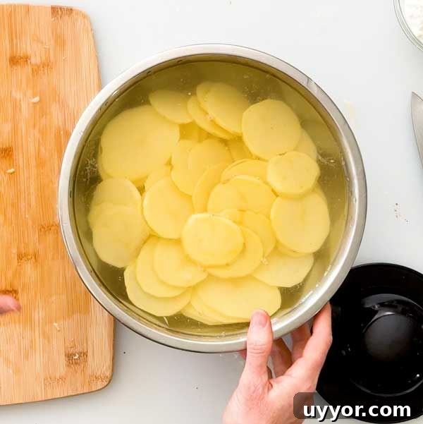 Sliced Yukon gold potatoes soaking in a bowl of water.