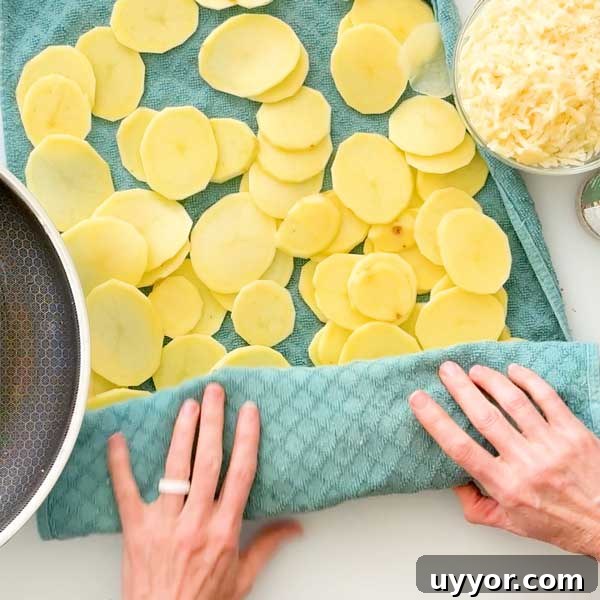 Spreading sliced potatoes out on a kitchen towel to soak up excess water.
