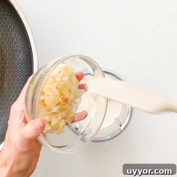 Adding sautéed onions and garlic to the blender cup.