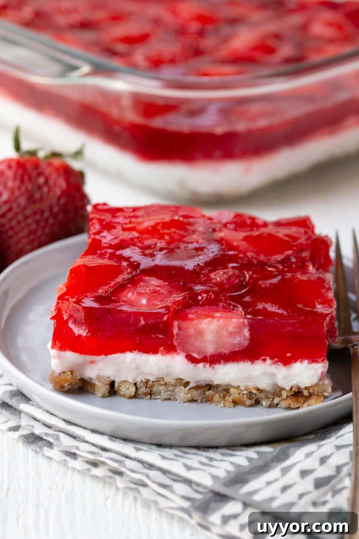 Strawberry Pretzel Salad Recipe with Creamy Cheesecake Layer 2 slice of layered dessert with a pretzel crust, creamy center, and strawberry jello topping.