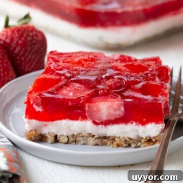 Strawberry Pretzel Salad Recipe with Creamy Cheesecake Layer 11 slice of a layered dessert with a pretzel crust, cream cheese filling, and strawberry gelatin on top.