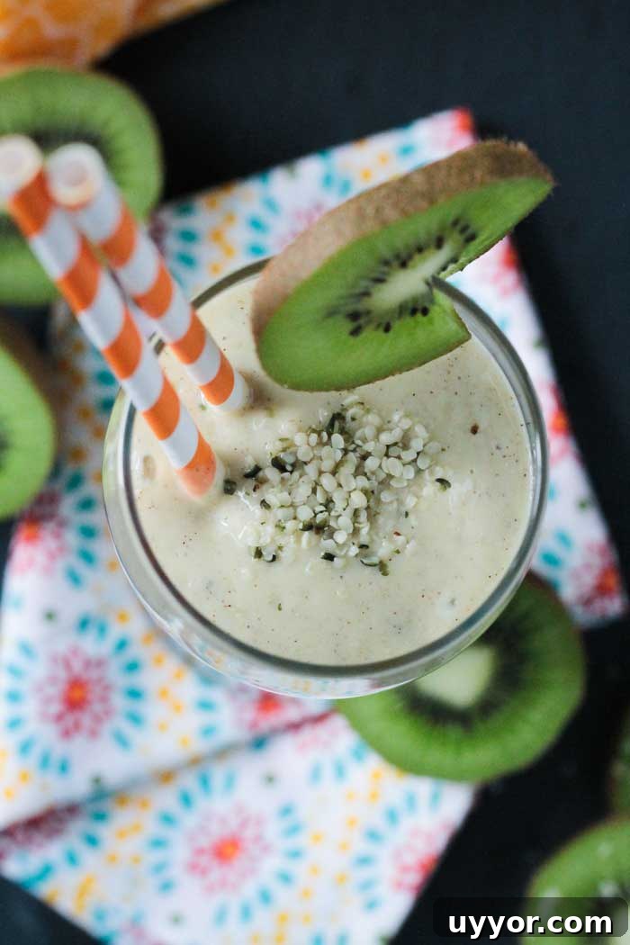 Mango Kiwi Smoothie with Hemp Hearts - A tropical twist on a creamy smoothie. Sweetened only with fruit. Loaded with vitamin C, a good amount of protein and healthy fats. Looking down into a glass of kiwi mango smoothie with hemp hearts sprinkled on top.