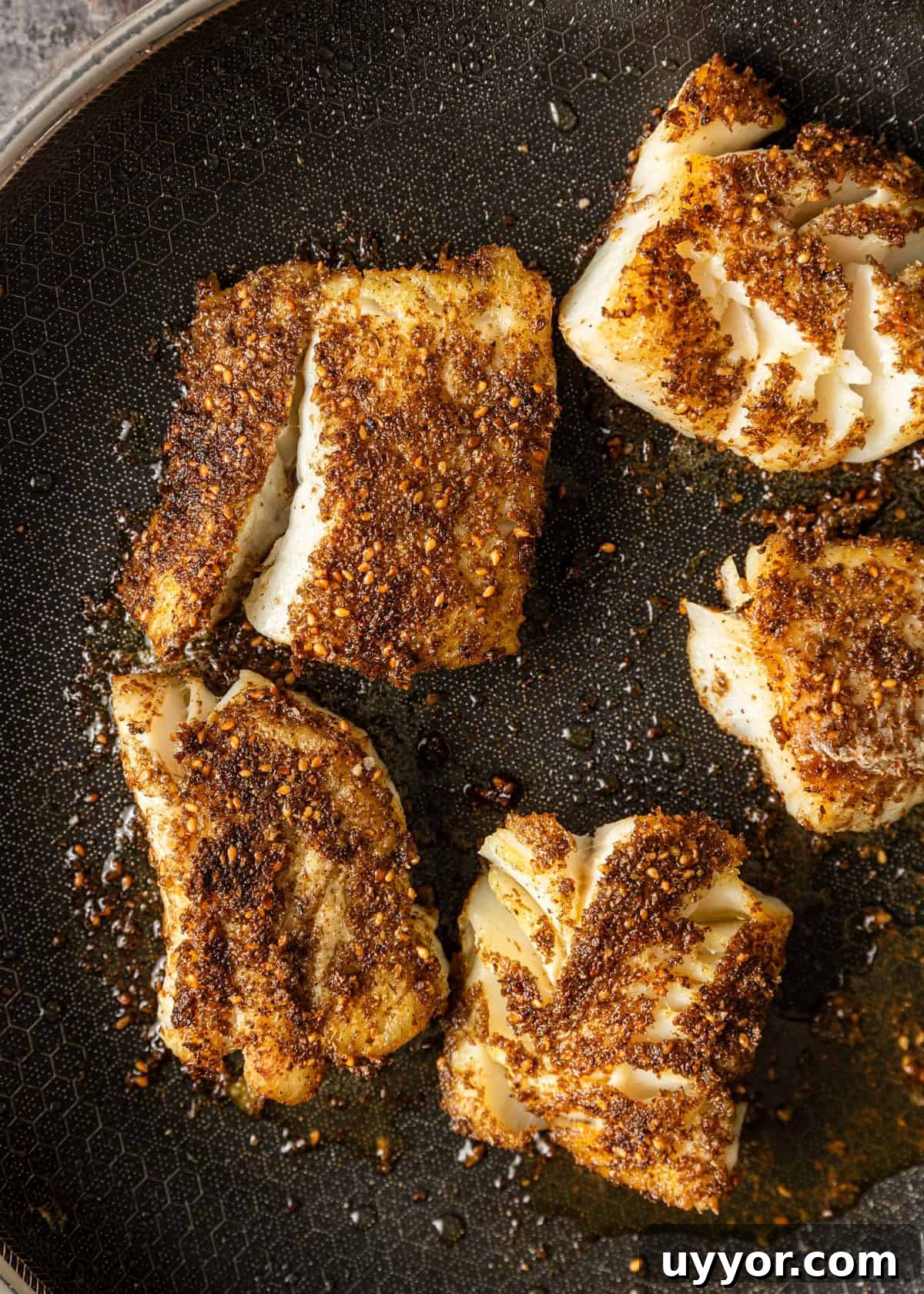 overhead closeup: pan fried cod cooking in a skillet
