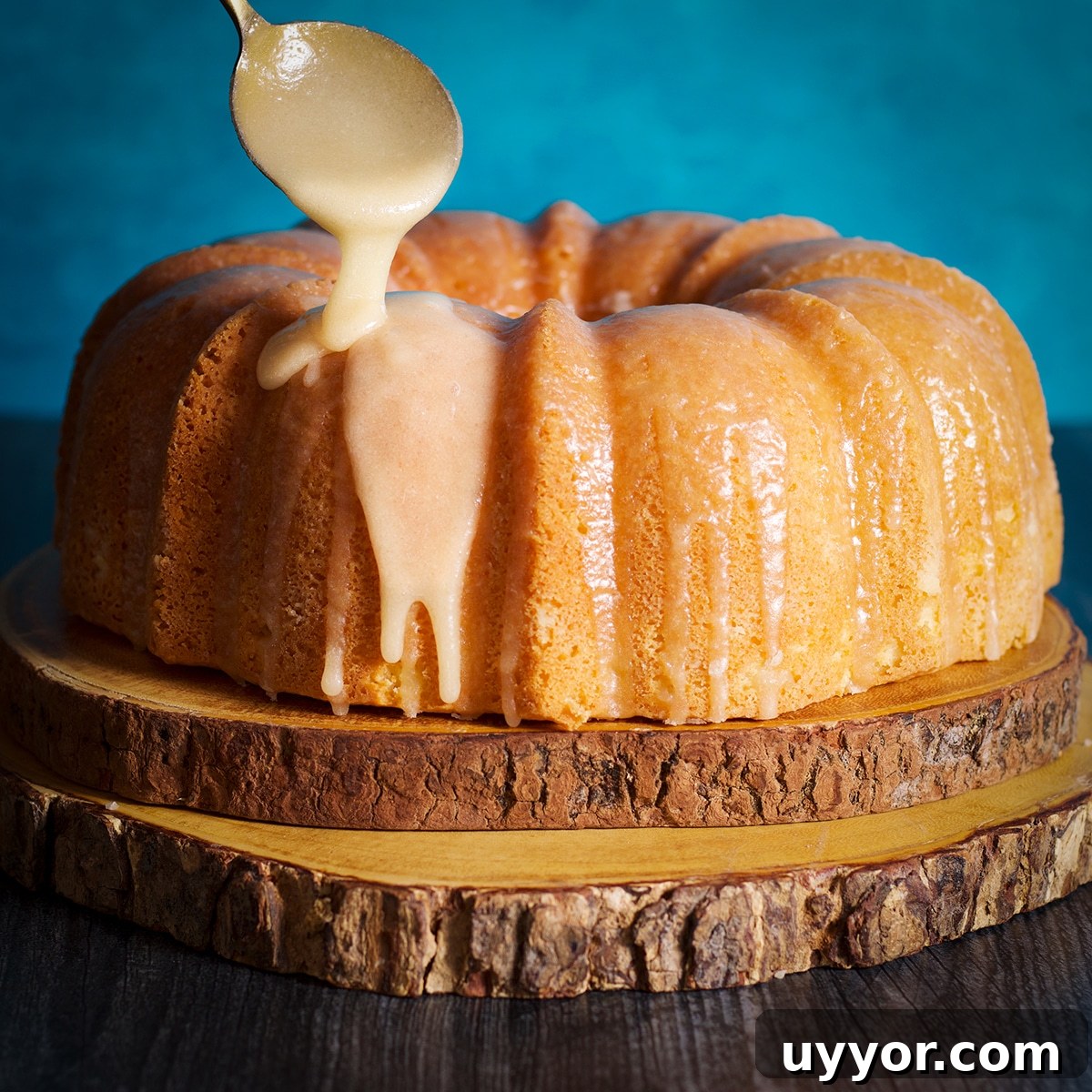 Lemon Bundt Cake with Zesty Tart Lemon Glaze 15 Someone using a spoon to drizzle lemon icing over the top of a lemon bundt cake.