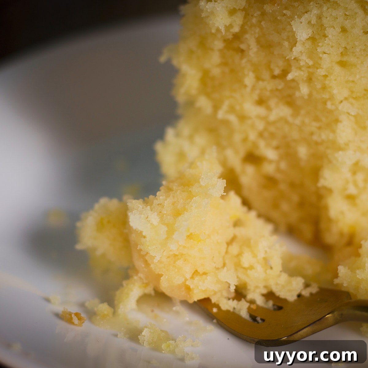 Lemon Bundt Cake with Zesty Tart Lemon Glaze 19 Someone using a fork to cut a bite of lemon bundt cake from a slice.