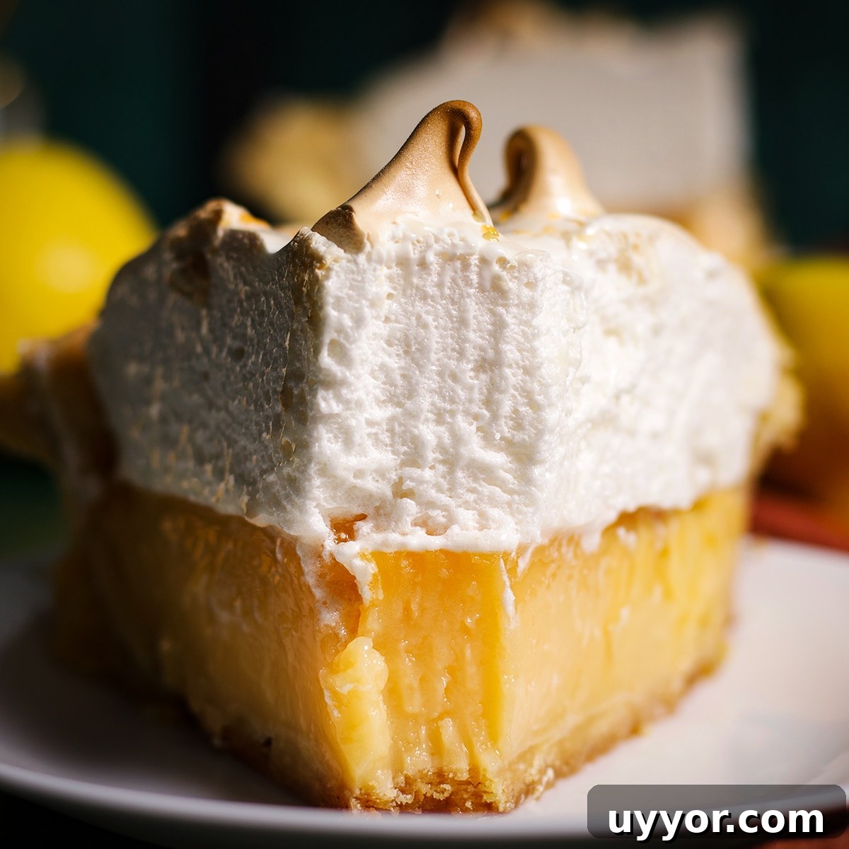 A slice of lemon meringue pie with a bite taken out of it.