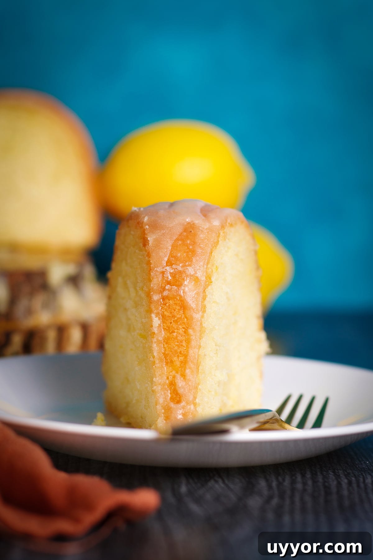 Lemon Bundt Cake with Zesty Tart Lemon Glaze 4 A slice of lemon bundt cake on a plate with a fork.
