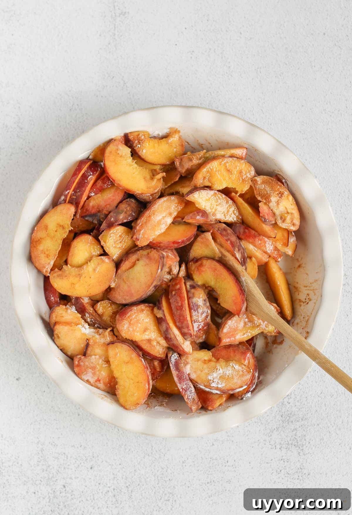Whole-Grain Peach Crisp with Low Sugar Recipe 5 Slice fresh peaches in a ceramic pie dish mixed with cinnamon and tapioca starch.