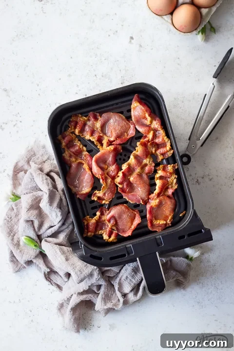 Air Fryer Cooking Times UK: Quick Guide by Food Type 6 Cooked back bacon in an air fryer drawer with tongs