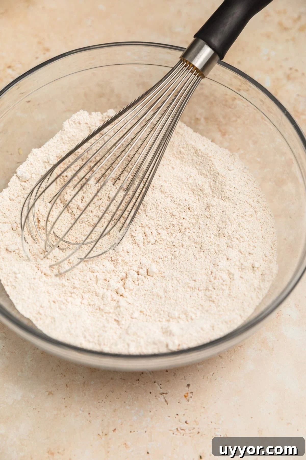A bowl of oat flour with a whisk in it.