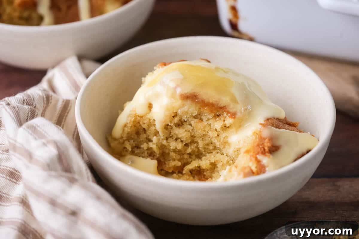Gluten-Free Lemon Curd Sponge Pudding Recipe for Zesty Dessert 13 Portion of lemon pudding in a bowl with custard poured over top and extra lemon curd drizzled over.