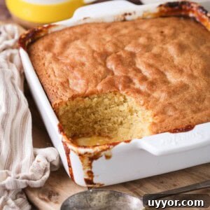 Gluten-Free Lemon Curd Sponge Pudding Recipe for Zesty Dessert 14 Lemon sponge pudding in a baking dish with a scoop taken out showing moist sponge.