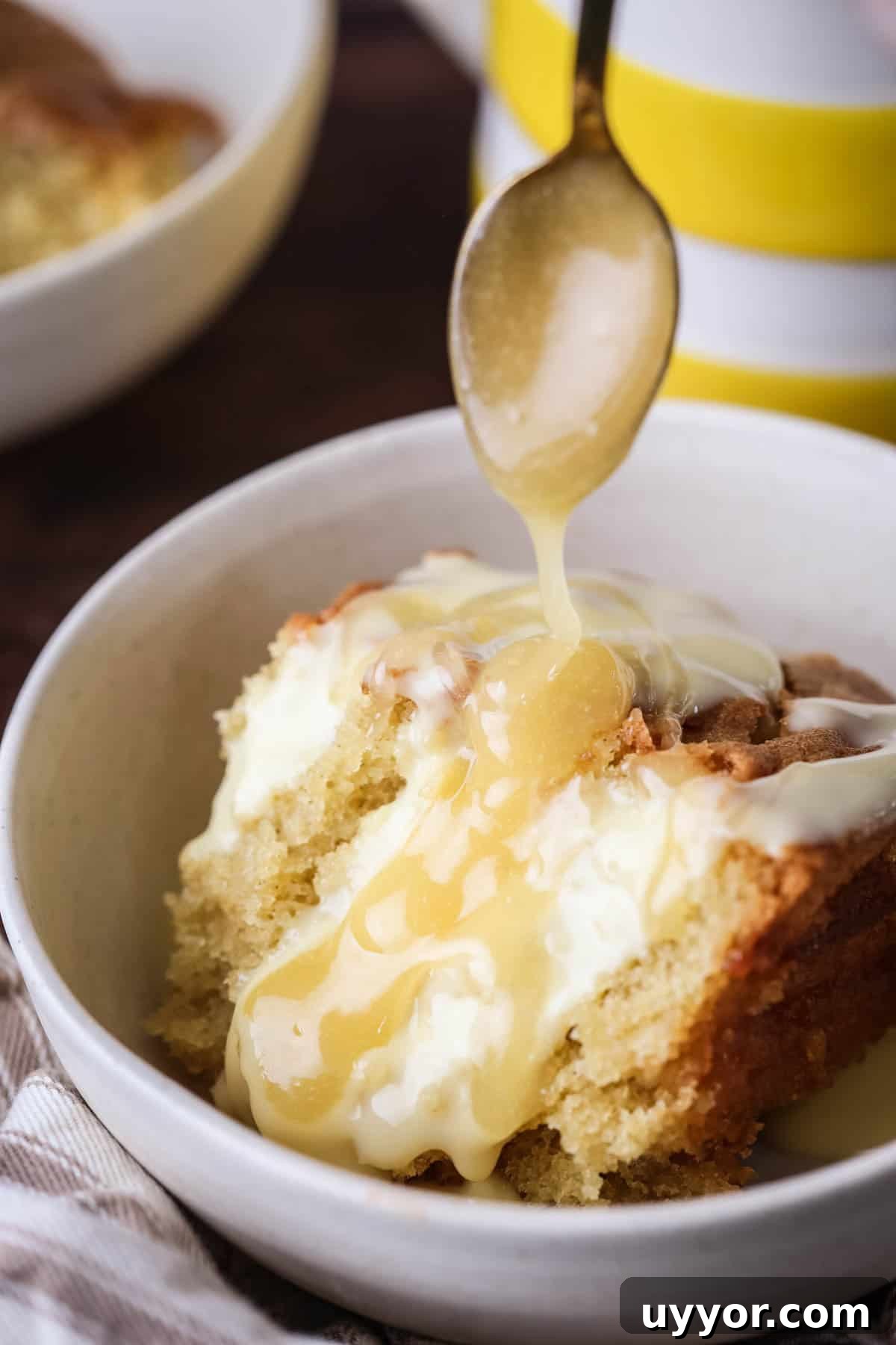 Gluten-Free Lemon Curd Sponge Pudding Recipe for Zesty Dessert 3 Portion of lemon pudding in a bowl with custard poured over top and extra lemon curd drizzled over.