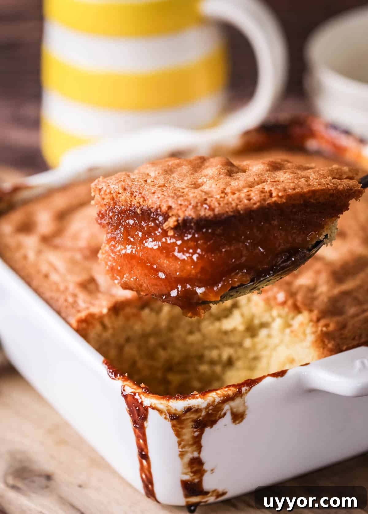 Gluten-Free Lemon Curd Sponge Pudding Recipe for Zesty Dessert 5 Lemon sponge pudding in a baking dish with a scoop taken out showing moist sponge with caramelised lemon crust.