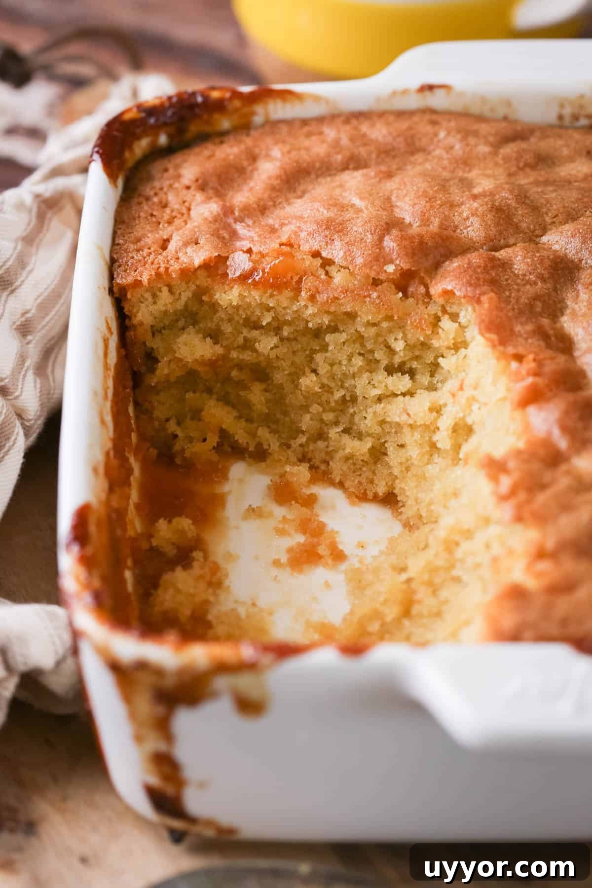 Gluten-Free Lemon Curd Sponge Pudding Recipe for Zesty Dessert 10 Lemon sponge pudding in a baking dish with a scoop taken out showing moist sponge.