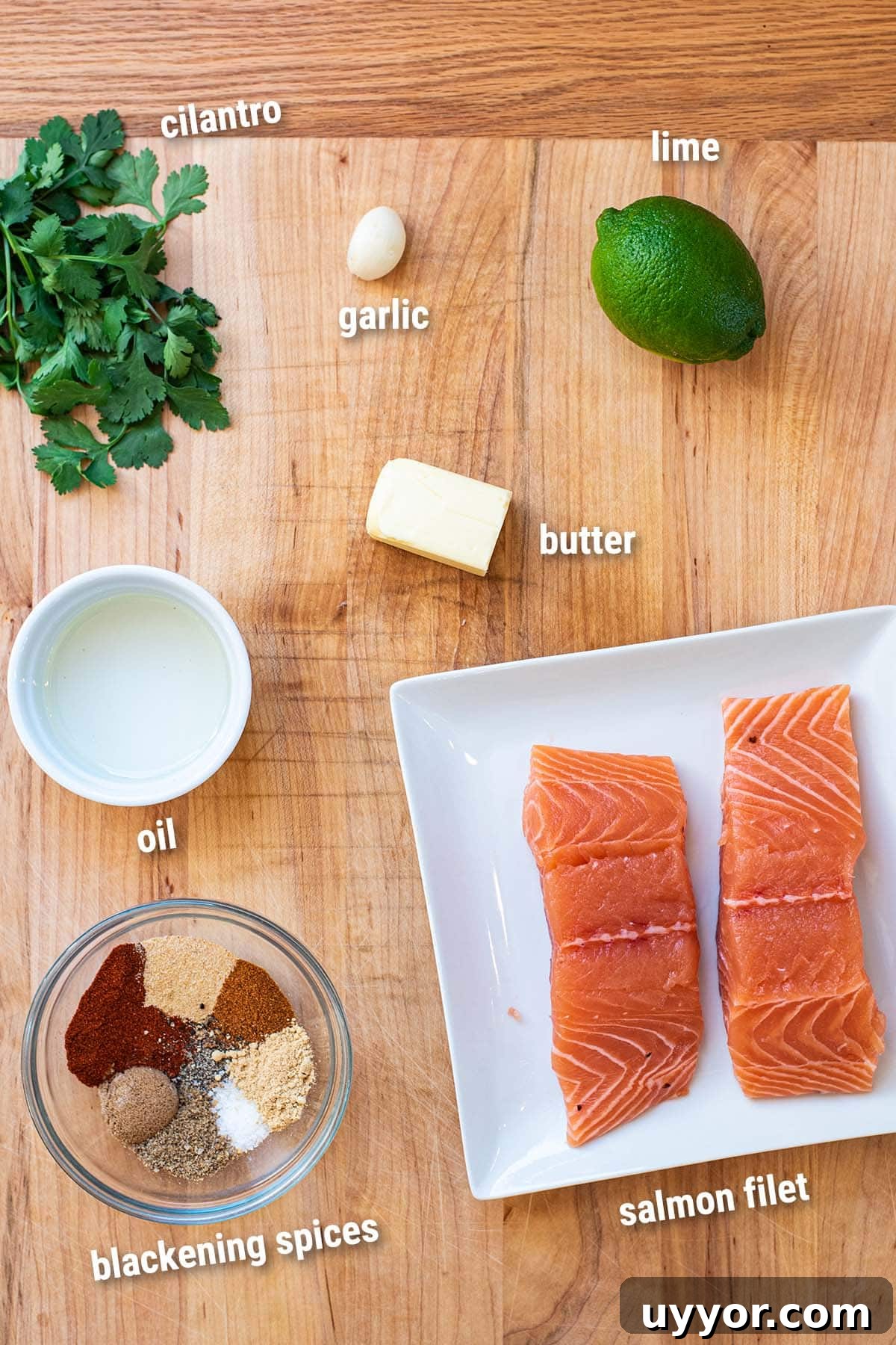 Raw, uncooked blackened salmon ingredients laid out on a wooden cutting board.