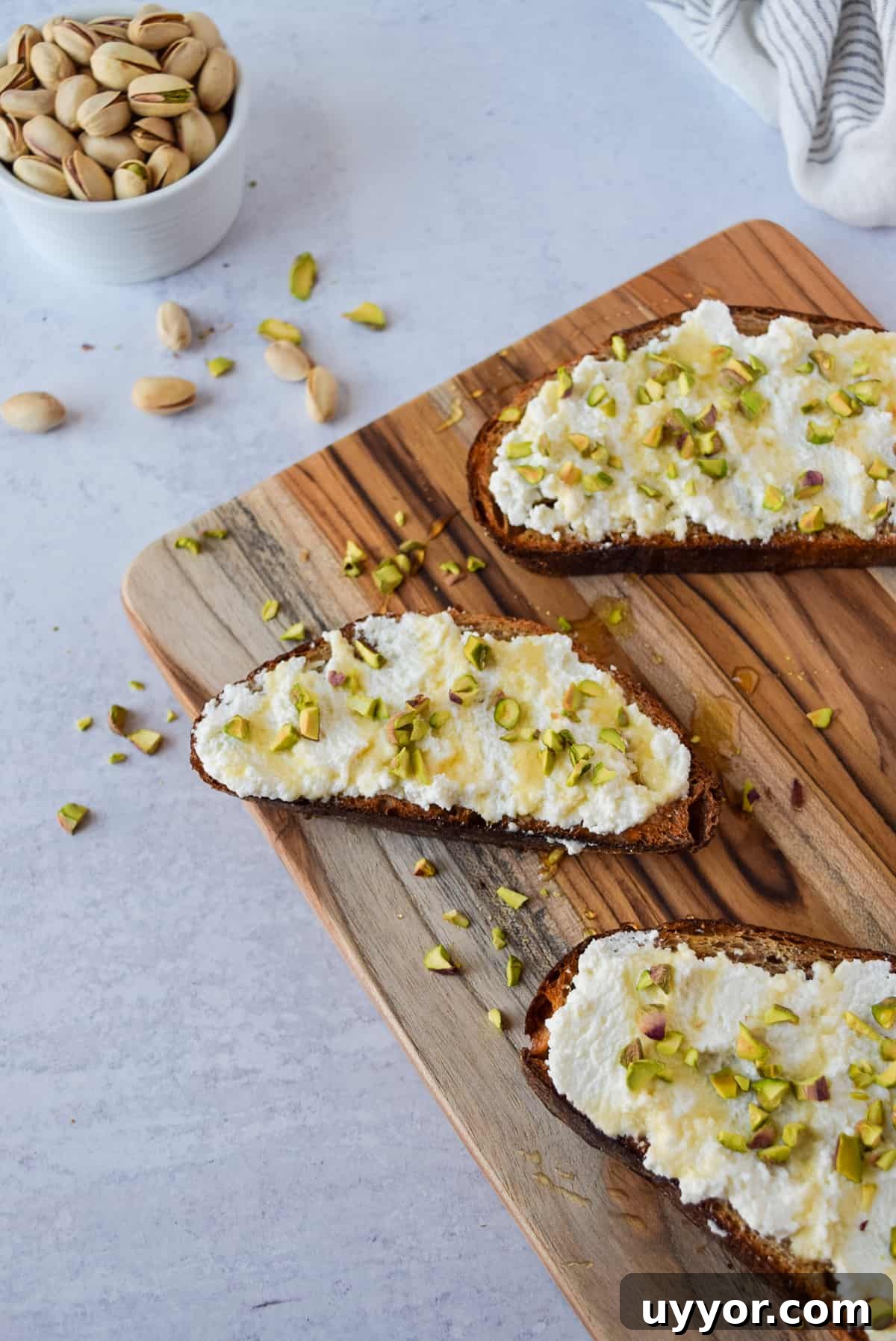 Ricotta Honey Toast with Pistachios on a cutting board.