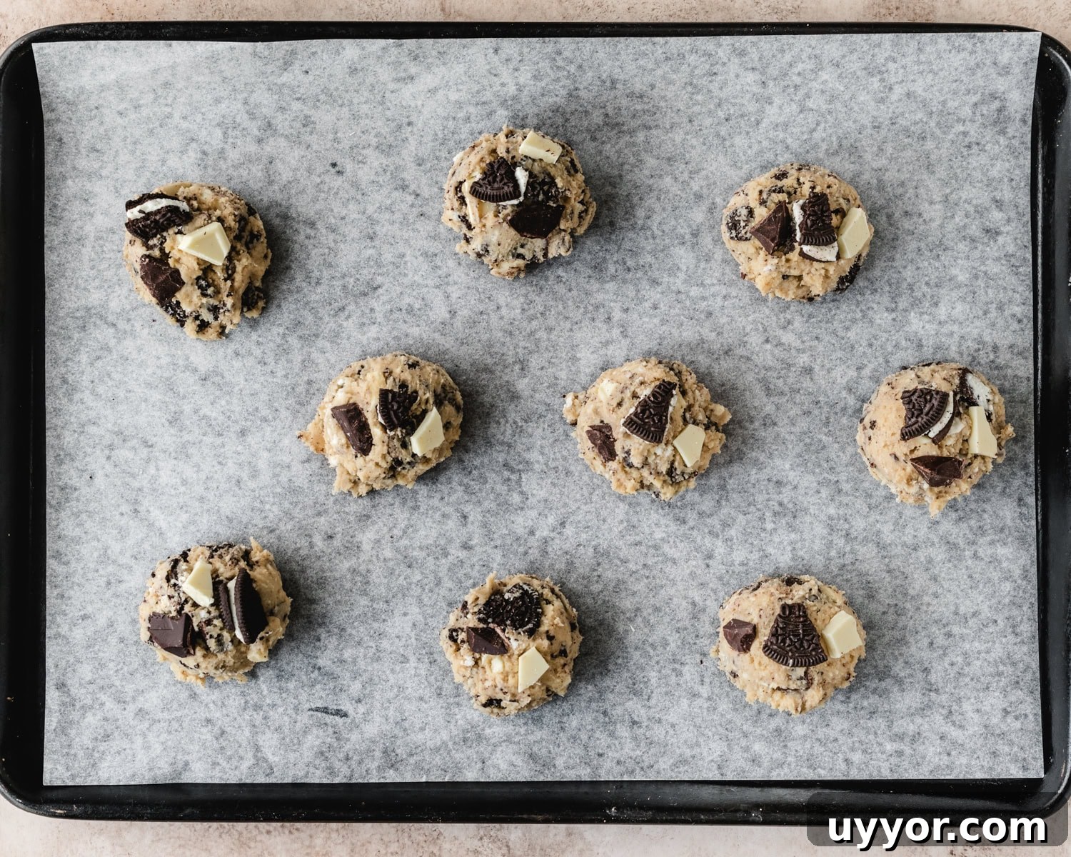 Cookie dough balls spaced about 2 inches apart on a parchment paper lined baking sheet.