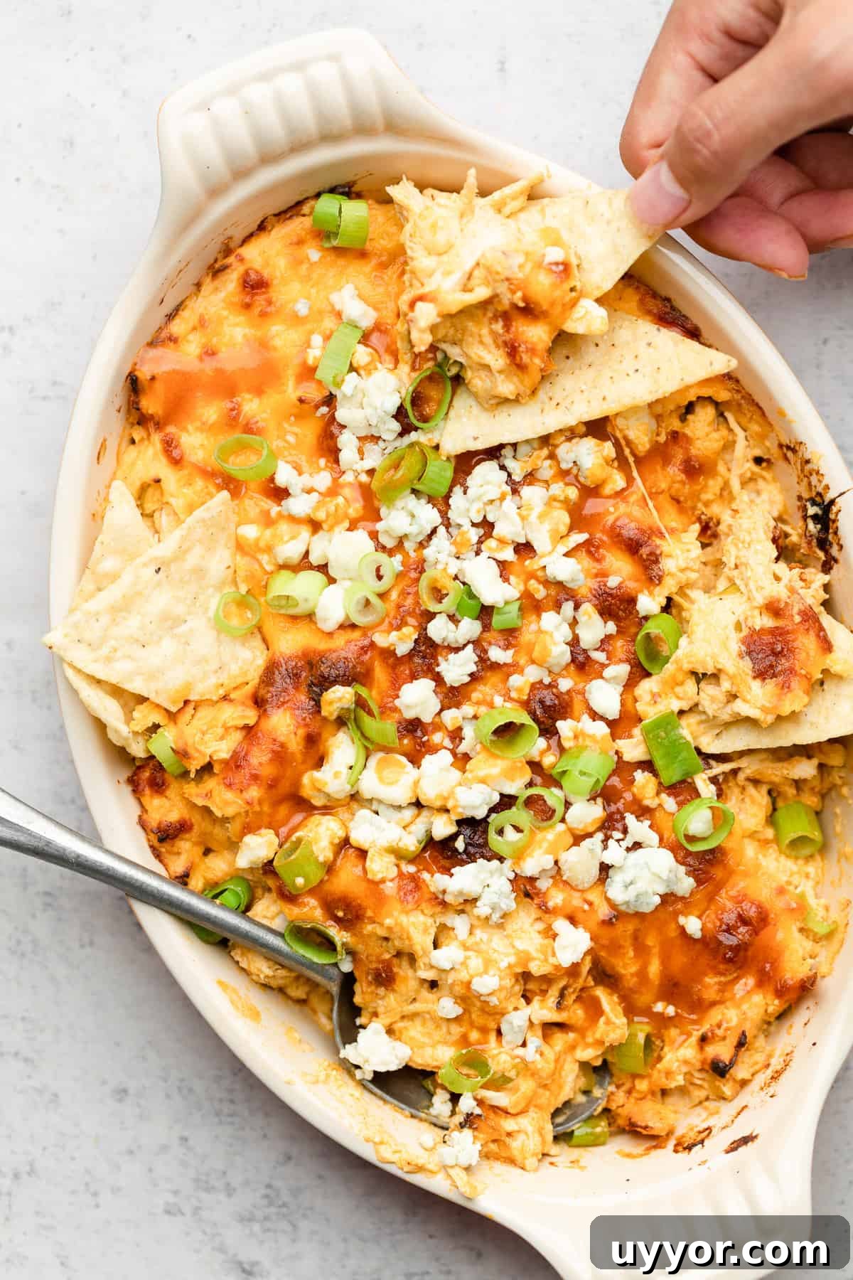 Lightened Buffalo Chicken Dip: Creamy, Tangy Game-Day Recipe 2 dipping chip into healthy buffalo chicken dip