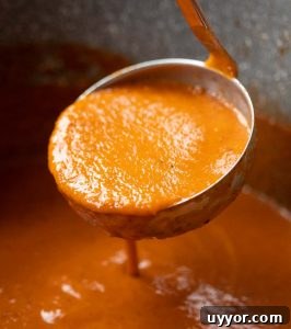 close up shot of ladle scooping up soup out of large pot