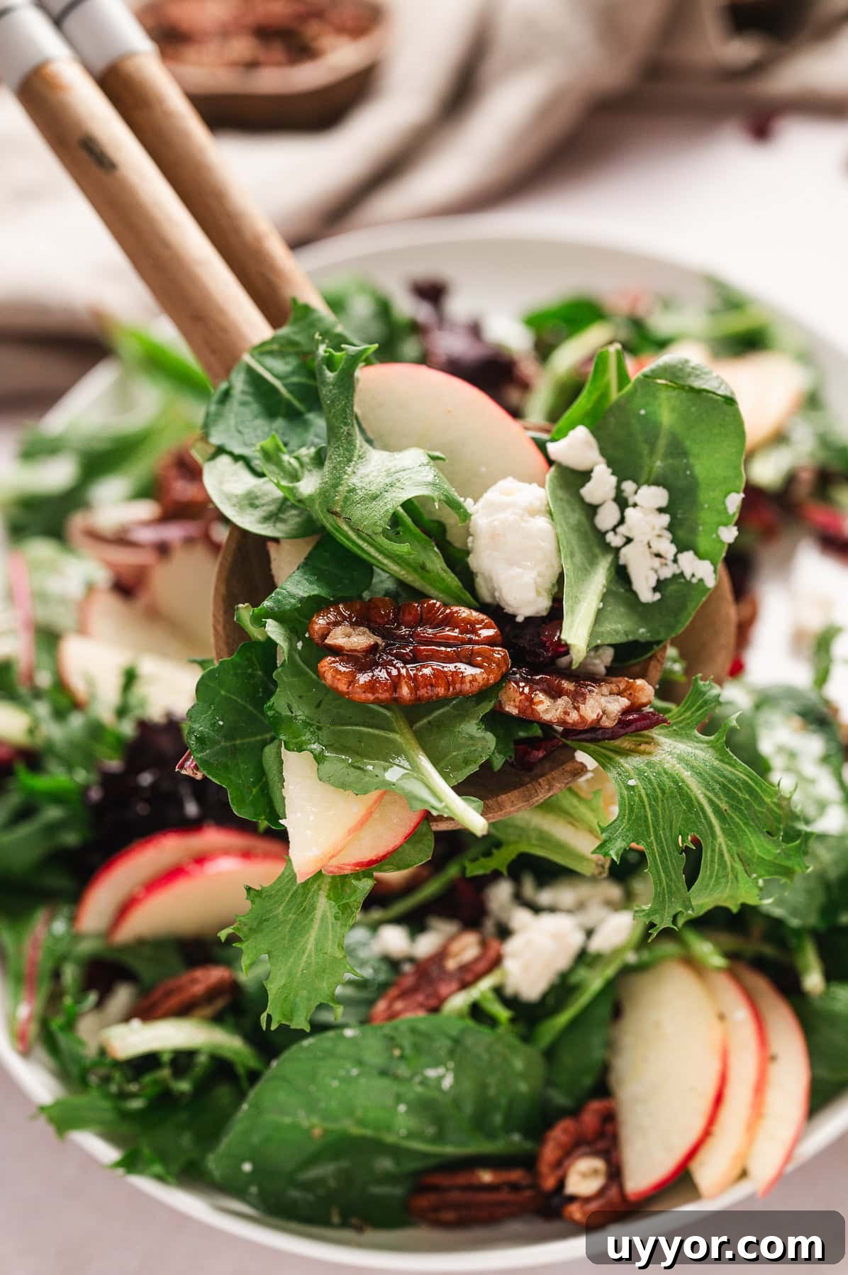 close up of apple pecan salad with tongs