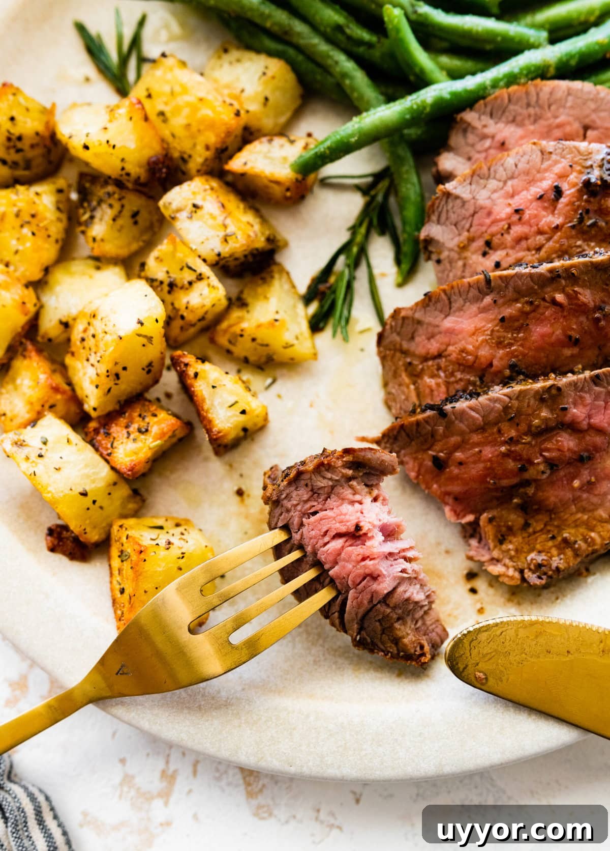 Serve the skillet tri-tip steak with potatoes and green beans. Bite taken out of the meat on a fork.