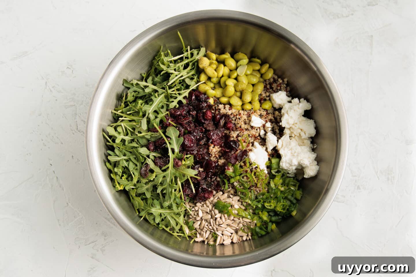 Bowl with all ingredients of quinoa arugula salad before being tossed together.