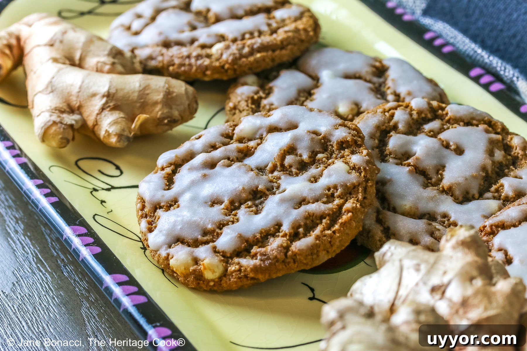 Iced cookies piled on a yellow rectangular platter. 