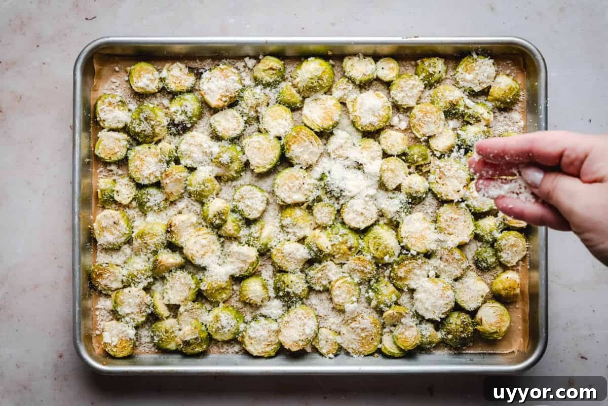 sprinkling parmesan over halved brussels sprouts on baking sheet.