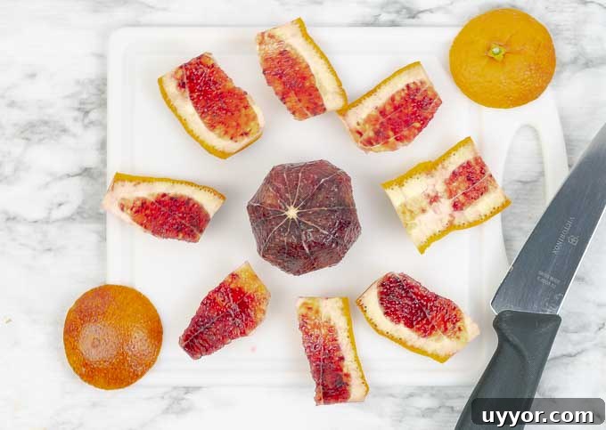 Demonstrating how to slice a blood orange on white cutting board