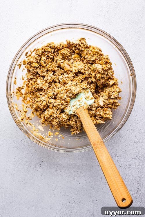 Tahini Sesame Granola with Honey & Orange 5 Tahini orange granola ingredients mixed in a glass bowl with a spatula.