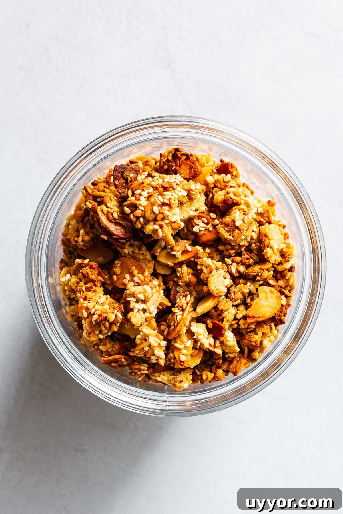Tahini Sesame Granola with Honey & Orange 8 Chunky tahini orange granola with sesame seeds and flaked almonds in glass jar.