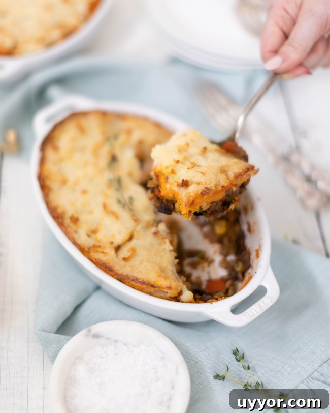Vegan Lentil Shepherd’s Pie Recipe for Comforting Dinners 2 scoop pulling out a slice of homemade vegan shepherd's pie