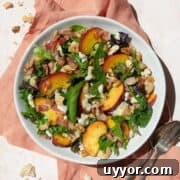Fresh Peach Salad with Honey-Lime Dressing Recipe 4 Peach salad in a white bowl on a peach colored linen, with a spoon and fork on the side.