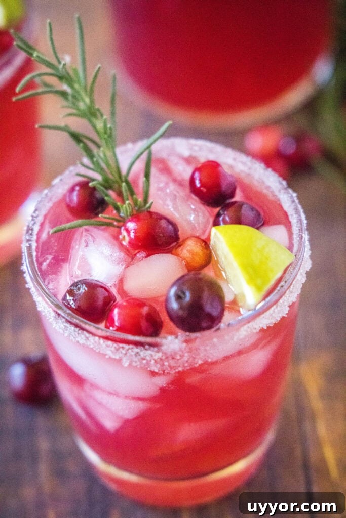 Mistletoe Margarita Cocktail Recipe for Holiday Parties 4 looking down on a glass with ice , cranberries, and a rosemary sprig